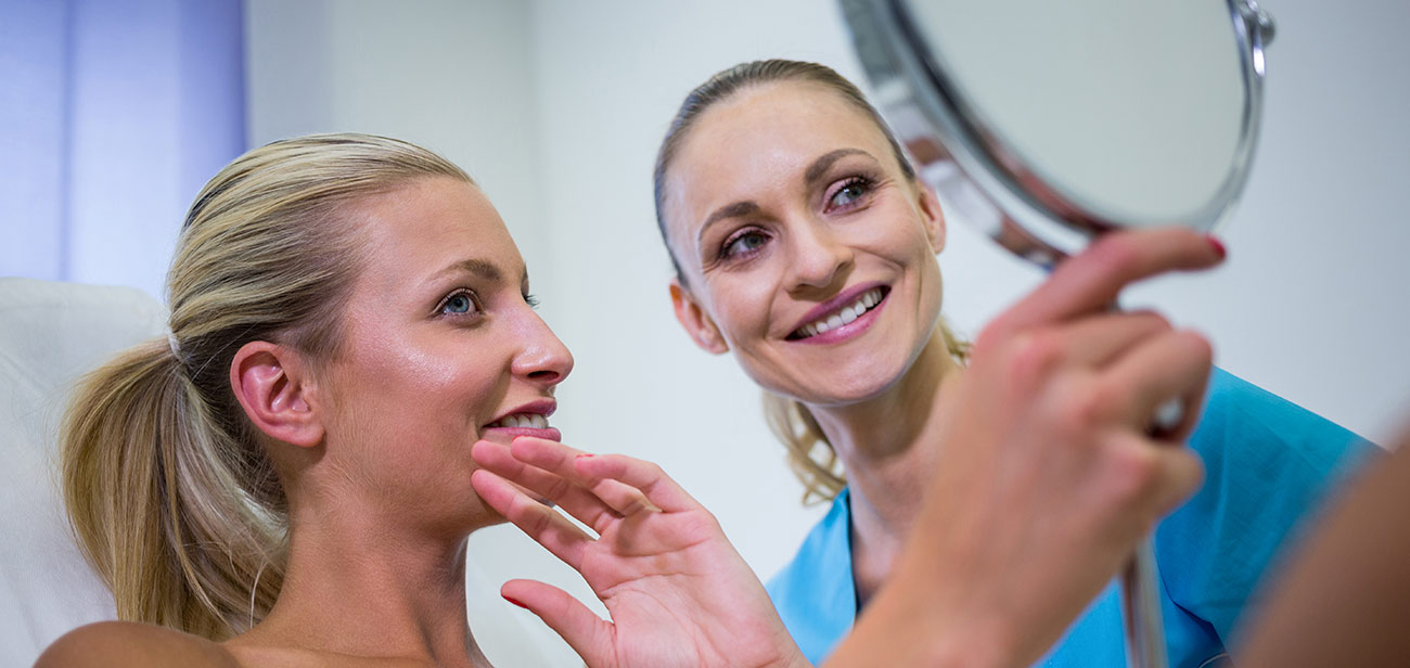 Woman checking smoother skin in the mirror after microneedling in Rockville, MD